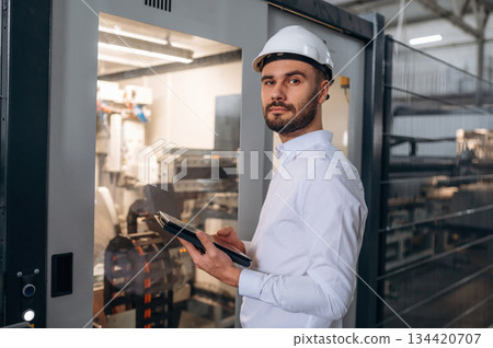 Manager is in white shirt. Man is working in the modern factory 134420707