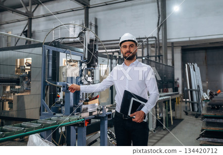 Manager is in white shirt. Man is working in the modern factory Manager is in white shirt. Man is working in the modern factory 134420712
