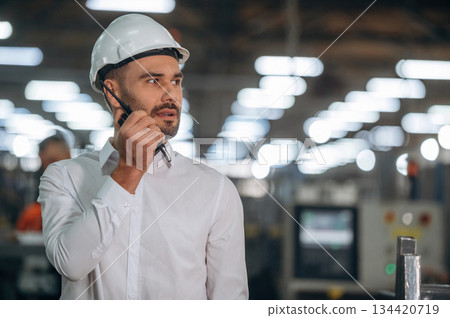 Talking by a walkie talkie. Man is working in the modern factory Talking by a walkie talkie. Man is working in the modern factory 134420719