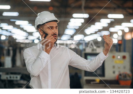 Talking by a walkie talkie. Man is working in the modern factory 134420723