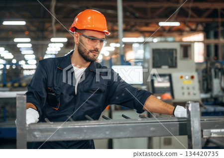 Metal pieces, standing. Man is working in the modern factory Metal pieces, standing. Man is working in the modern factory 134420735