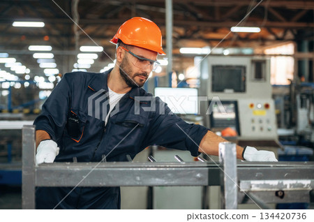 Metal pieces, standing. Man is working in the modern factory Metal pieces, standing. Man is working in the modern factory 134420736