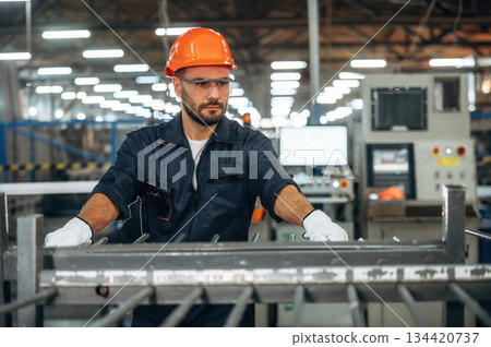 Metal pieces, standing. Man is working in the modern factory Metal pieces, standing. Man is working in the modern factory 134420737
