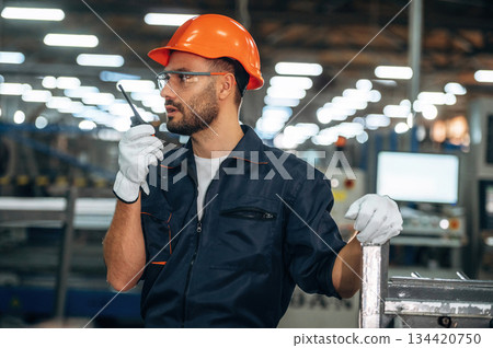 Communication by the radio, walkie talkie. Man is working in the modern factory Communication by the radio, walkie talkie. Man is working in the modern factory 134420750