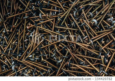 Many of the golden colored screws laying down, top view of quality products 134420782