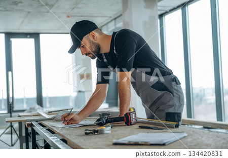 Writing on the paper. A man is renovating an unfinished room 134420831