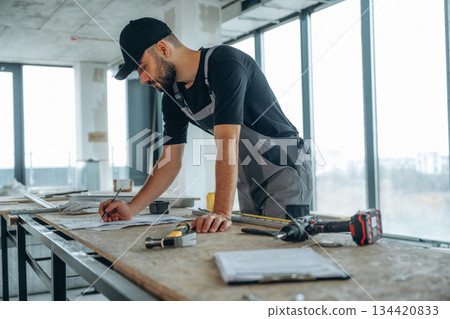Writing on the paper. A man is renovating an unfinished room 134420833