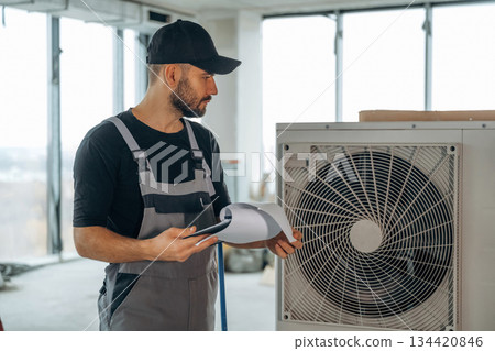 Big air conditioner. A man is renovating an unfinished room Big air conditioner. A man is renovating an unfinished room 134420846