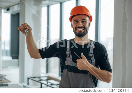 Happy construction worker is holding keys for new home 134420884