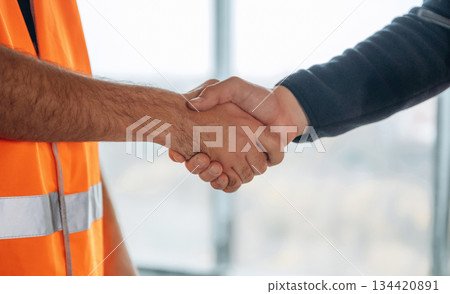 Close up view of two construction site workers making handshake, meet Close up view of two construction site workers making handshake, meet 134420891