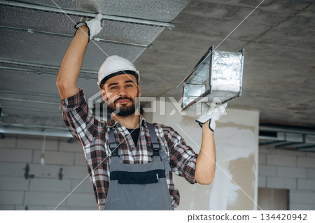 Ready to install the piece to the ceiling. A man is renovating an unfinished room 134420942