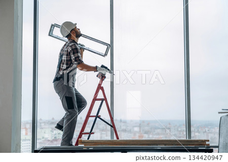 On the ladder. A man is renovating an unfinished room 134420947