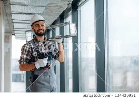 Handyman is with drill and metal piece for ceiling. A man is renovating an unfinished room Handyman is with drill and metal piece for ceiling. A man is renovating an unfinished room 134420951
