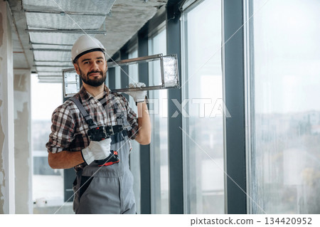Handyman is with drill and metal piece for ceiling. A man is renovating an unfinished room Handyman is with drill and metal piece for ceiling. A man is renovating an unfinished room 134420952