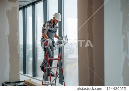 Near the windows. A man is renovating an unfinished room 134420955
