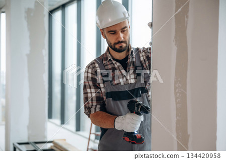 Drilling the wall. A man is renovating an unfinished room Drilling the wall. A man is renovating an unfinished room 134420958