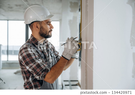 Focused on the work. A man is renovating an unfinished room 134420971