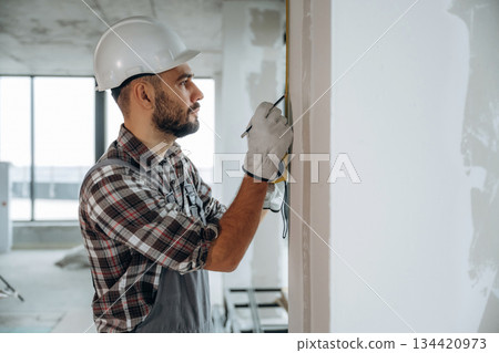 View from the side. A man is renovating an unfinished room View from the side. A man is renovating an unfinished room 134420973