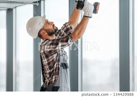 Hands are up, ceiling work. A man is renovating an unfinished room 134420986