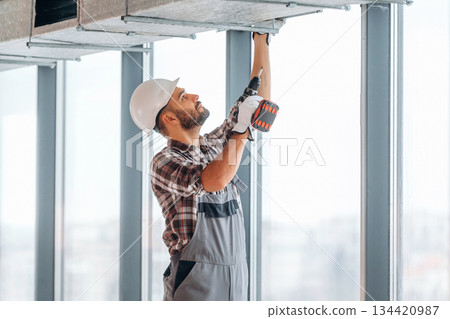 Hands are up, ceiling work. A man is renovating an unfinished room 134420987
