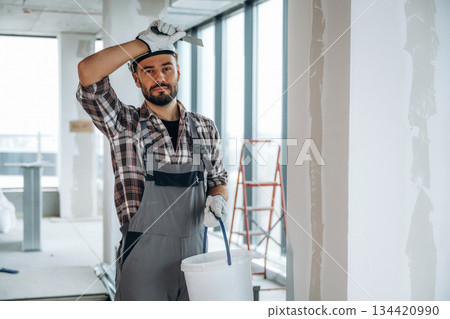 Taking a break. A man is renovating an unfinished room Taking a break. A man is renovating an unfinished room 134420990