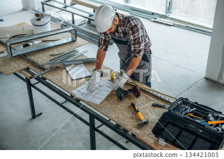 Top view, standing by the table. A man is renovating an unfinished room 134421003