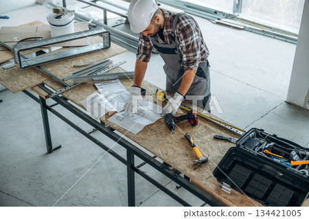 Top view, standing by the table. A man is renovating an unfinished room Top view, standing by the table. A man is renovating an unfinished room 134421005