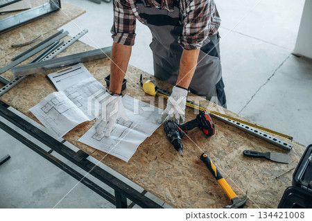 Focused, tools. Close up view of worker that is renovating unfinished room 134421008