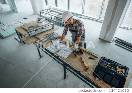 Wooden table with metal foundation. A man is renovating an unfinished room 134421010