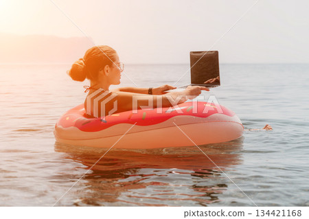 Woman Float Beach - Relaxing on a donut float in the ocean while reading a book. Woman Float Beach - Relaxing on a donut float in the ocean while reading a book. 134421168