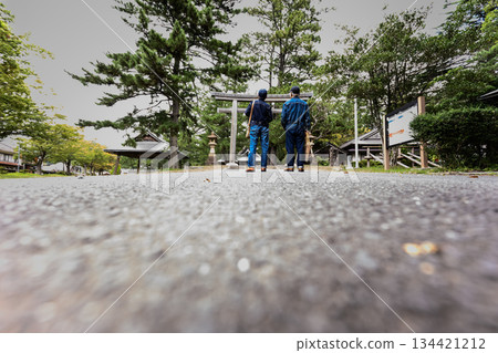 A senior couple in denim standing on the approach to a shrine 134421212