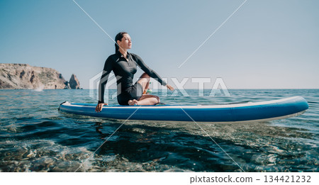 Yoga Paddleboard Woman Ocean - Woman practicing yoga on a paddleboard in the ocean on a sunny day. Yoga Paddleboard Woman Ocean - Woman practicing yoga on a paddleboard in the ocean on a sunny day. 134421232