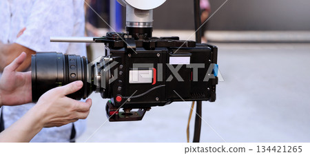 Behind the scenes of movie shooting or video production and film crew team with camera equipment at outdoor location. Video camera with professional robotic arm. BTS of Filming camera setup at outdoor 134421265