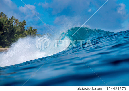 Energetic surf soaring over coral reef with dazzling sunlight reflections 134421273