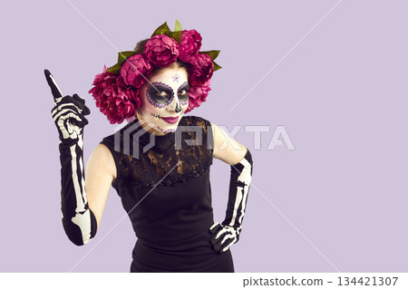 Beautiful cheerful woman with Mexican-style Halloween face art has new funny idea. Beautiful cheerful woman with Mexican-style Halloween face art has new funny idea. 134421307