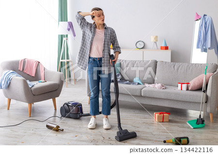 Tired young woman vacuuming her house after party, wiping her forehead, feeling tired of cleaning, free space. Exhausted millennial student getting rid of mess at university dorm room Tired young woman vacuuming her house after party, wiping her forehead, feeling tired of cleaning, free space. Exhausted millennial student getting rid of mess at university dorm room 134422116