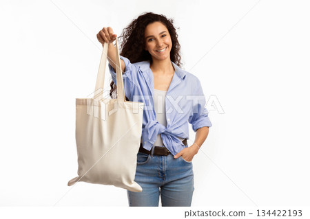 Smiling Lady Showing White Eco Bag To Camera Standing Over White Studio Background. Female Customer Posing With Eco-Friendly Textile Shopper Handbag. Stop Using Plastic, Shopping And Ecology 134422193