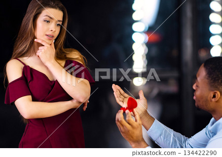 Black Man Begging Girlfriend To Marry Him, Making Marriage Proposal In Restaurant. Young Woman Hesitating With Answer, Having Doubts To Say Yes Or No, Standing With Thoughtful Face Expression Black Man Begging Girlfriend To Marry Him, Making Marriage Proposal In Restaurant. Young Woman Hesitating With Answer, Having Doubts To Say Yes Or No, Standing With Thoughtful Face Expression 134422290