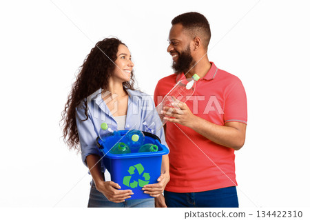 Waste Sorting. Multicultural Family Couple Sorting Junk Posing Holding Box With Recycle Symbol Full Of Used Plastic Bottles Standing Over White Background. Studio Shot. Trash Disposal Concept 134422310