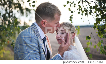 Newlyweds embracing beneath birch branches, showcasing intimate wedding day connection and heartfelt romantic emotion Newlyweds embracing beneath birch branches, showcasing intimate wedding day connection and heartfelt romantic emotion 134422461