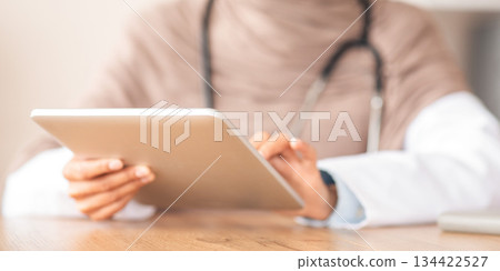 Modern technologies in healthcare, online doctor concept. Digital tablet in unrecognizable female doctor hands, closeup. Physician woman in hijab using pad, working online Modern technologies in healthcare, online doctor concept. Digital tablet in unrecognizable female doctor hands, closeup. Physician woman in hijab using pad, working online 134422527