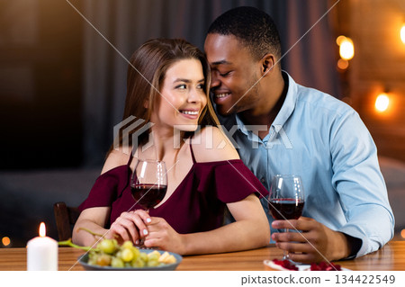 Interracial Love. Portrait Of Happy Multicultural Couple On Romantic Date In Restaurant, Black Guy And White Girl Drinking Wine And Enjoying Time Together, Multiracial Lovers Smiling And Flirting Interracial Love. Portrait Of Happy Multicultural Couple On Romantic Date In Restaurant, Black Guy And White Girl Drinking Wine And Enjoying Time Together, Multiracial Lovers Smiling And Flirting 134422549