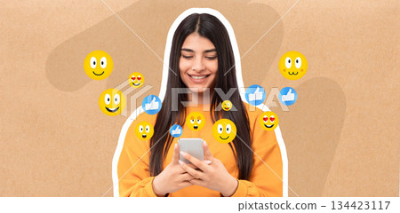 A young woman smiles while texting on her smartphone in a casual setting. Colorful emojis surround her, reflecting a joyful interaction on social media. A young woman smiles while texting on her smartphone in a casual setting. Colorful emojis surround her, reflecting a joyful interaction on social media. 134423117