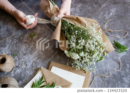 Crafting with natural elements using freshly picked flowers in a creative workspace Crafting with natural elements using freshly picked flowers in a creative workspace 134423320