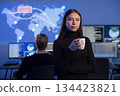 Female cybersecurity analyst in control room with team evaluating global threats 134423821