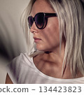 Stylish woman wearing sunglasses with soft shadow overlay on a neutral background 134423823