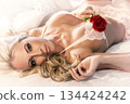 Sexy Woman in Lingerie Laying on a Bed Holding a Red Rose 134424242