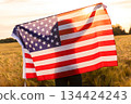 Silhouette of Young Woman Holding USA Flag in Field at Sunset 134424243