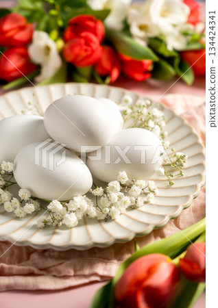 Easter, spring floral background. Red tulips, Fresia and white eggs, flowers on pink background 134424341