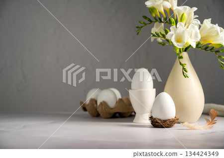 Spring, Easter background. White freesias flowers in a vase with white eggs. Spring, Easter background. White freesias flowers in a vase with white eggs. 134424349
